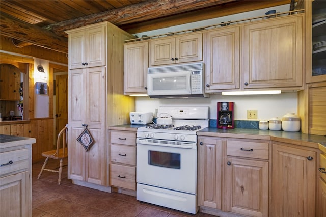 kitchen featuring white appliances, wooden ceiling, dark tile patterned floors, wooden walls, and light brown cabinets