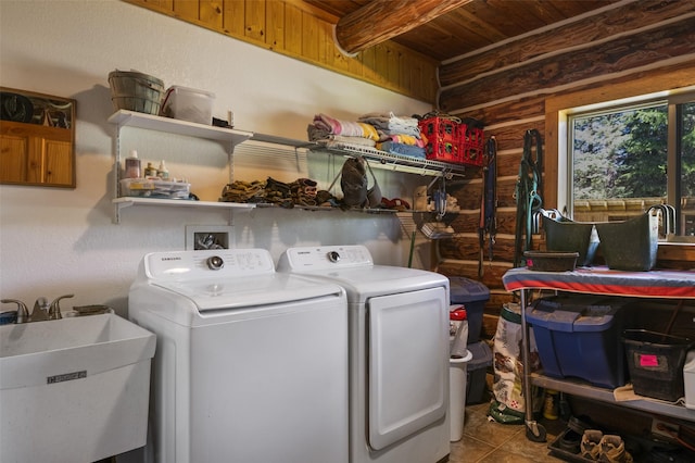 clothes washing area with washing machine and clothes dryer, rustic walls, sink, wooden ceiling, and tile patterned flooring