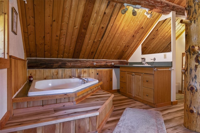 bathroom featuring a tub to relax in, hardwood / wood-style floors, wooden ceiling, vaulted ceiling with beams, and vanity