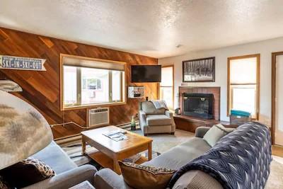 living room featuring a tiled fireplace, wooden walls, a wall mounted AC, and a textured ceiling