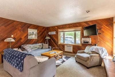 living room featuring carpet, a wall unit AC, and wood walls