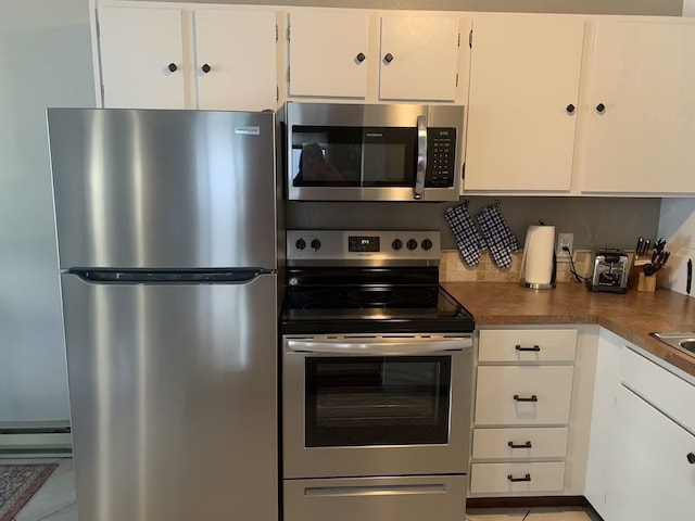 kitchen with baseboard heating, white cabinetry, light tile patterned floors, and stainless steel appliances