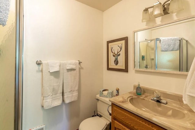 bathroom featuring vanity, an enclosed shower, and toilet