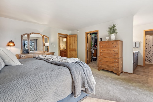 carpeted bedroom featuring ensuite bathroom, a spacious closet, and a closet