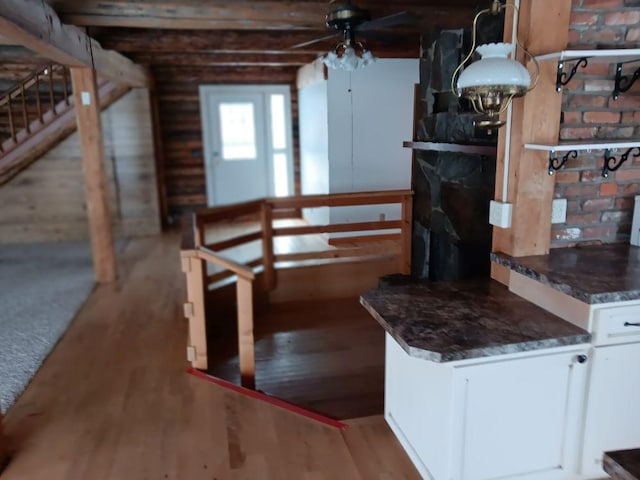 interior space with light wood-type flooring, white cabinetry, ceiling fan, and dark stone counters