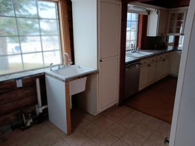 kitchen featuring dishwasher, white cabinets, sink, light tile patterned floors, and kitchen peninsula