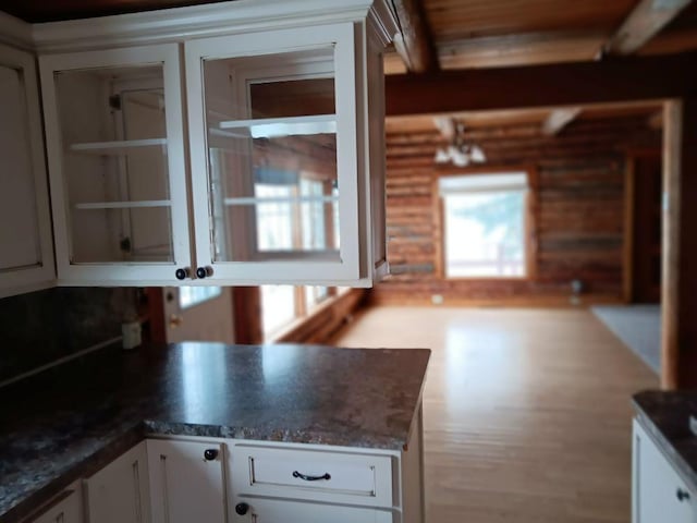 kitchen with kitchen peninsula, white cabinetry, and dark stone countertops