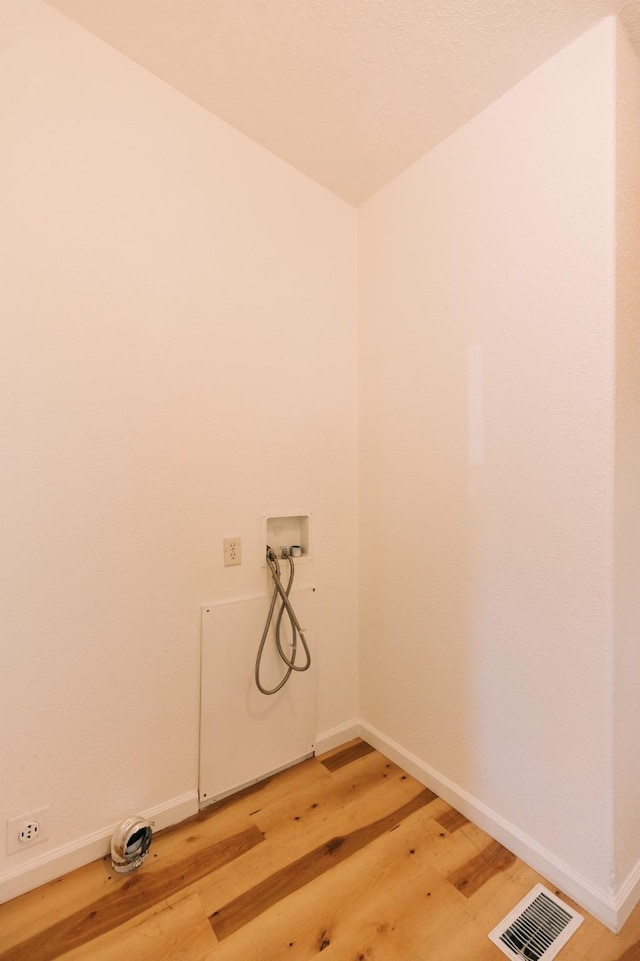 clothes washing area with light wood-type flooring and hookup for a washing machine