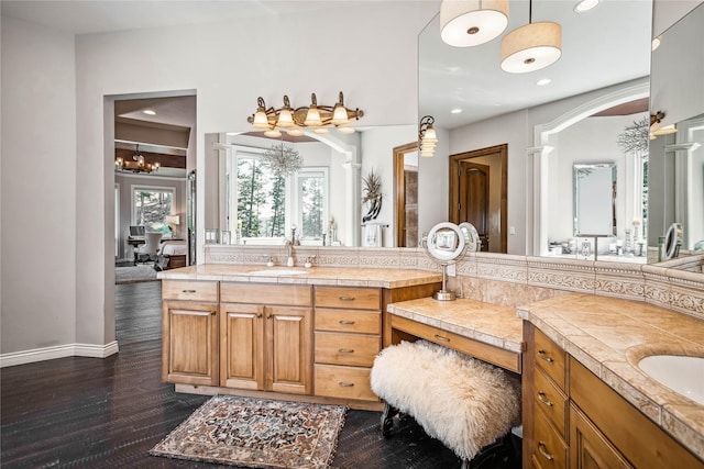 bathroom featuring wood finished floors, ensuite bath, two vanities, recessed lighting, and a sink