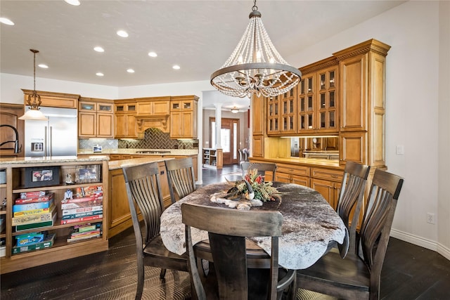 dining room featuring a notable chandelier, dark wood-style floors, recessed lighting, decorative columns, and baseboards