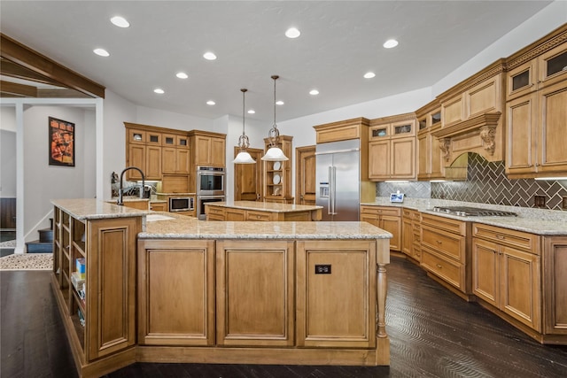 kitchen with tasteful backsplash, a center island with sink, appliances with stainless steel finishes, dark wood-style floors, and a sink