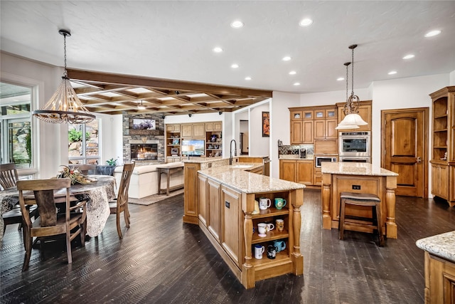 kitchen with brown cabinetry, a stone fireplace, a large island with sink, and open shelves