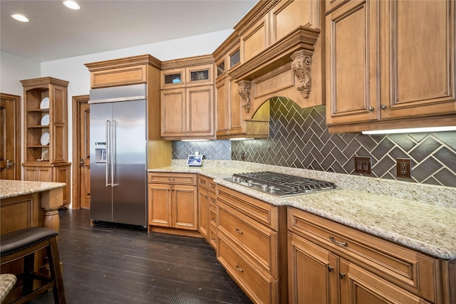 kitchen with light stone counters, stainless steel appliances, glass insert cabinets, and dark wood-type flooring