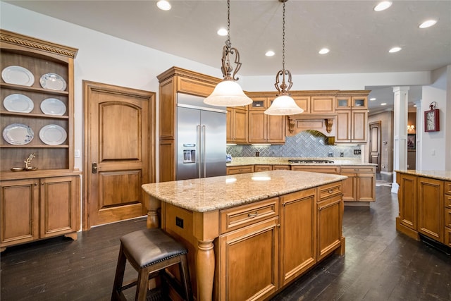 kitchen featuring dark wood finished floors, a kitchen island, stainless steel appliances, and decorative columns