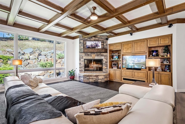 living room with dark wood-style floors, baseboards, coffered ceiling, a stone fireplace, and beamed ceiling