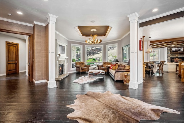 living area with a lit fireplace, a chandelier, and ornate columns