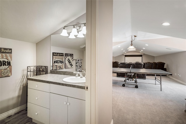 bathroom with baseboards, vanity, and lofted ceiling