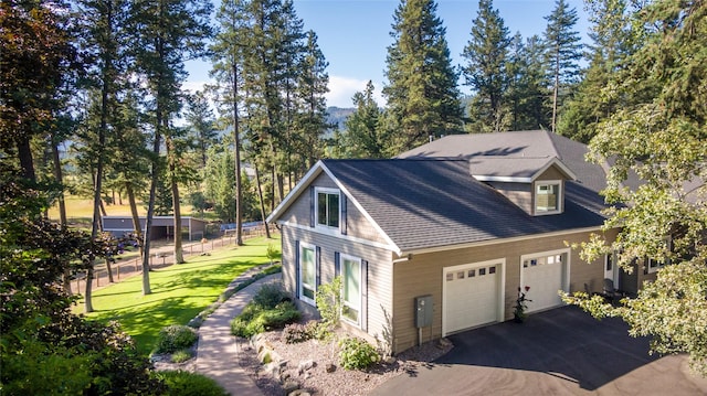 view of side of property featuring a lawn, driveway, fence, roof with shingles, and an attached garage