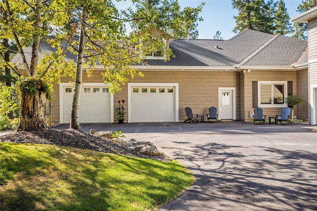 exterior space with driveway, a shingled roof, and a garage