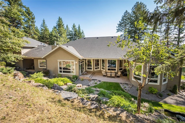 back of property featuring a shingled roof and a patio