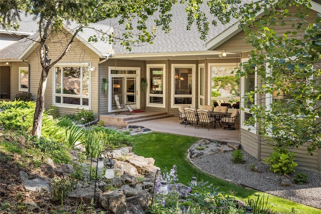 rear view of house featuring a patio and roof with shingles