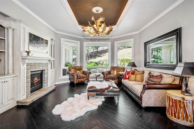 living room featuring a chandelier, a fireplace, crown molding, and a tray ceiling