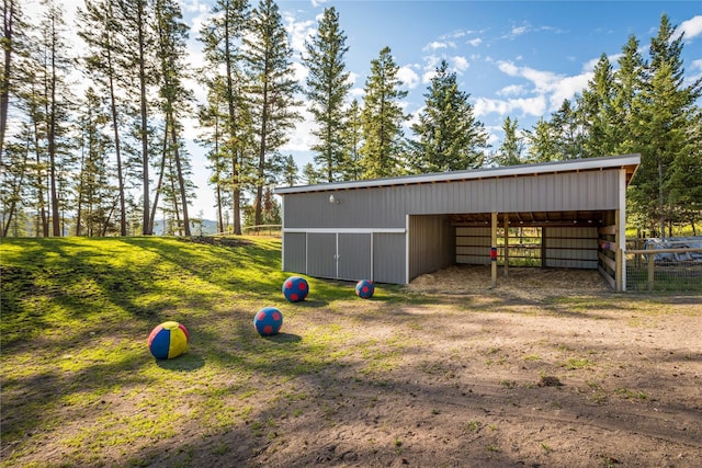 view of pole building with fence and dirt driveway