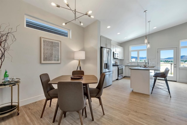 dining room with vaulted ceiling, sink, and light hardwood / wood-style flooring