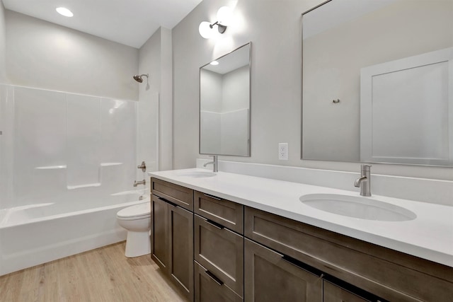 full bathroom with hardwood / wood-style flooring, washtub / shower combination, vanity, and toilet