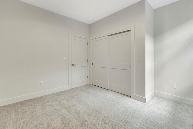 unfurnished bedroom featuring a closet and light colored carpet