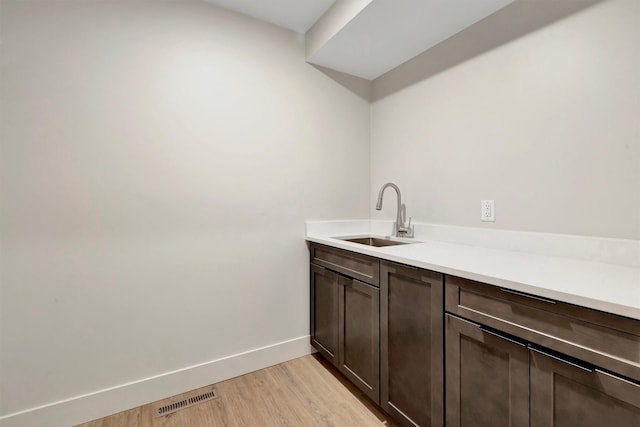 interior space with sink, light hardwood / wood-style floors, and dark brown cabinetry