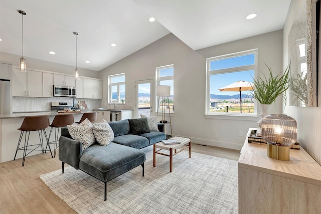 living room featuring lofted ceiling, sink, and light hardwood / wood-style floors