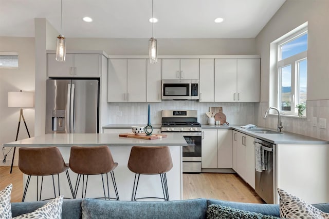 kitchen with white cabinetry, sink, hanging light fixtures, and appliances with stainless steel finishes