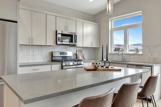 kitchen with decorative light fixtures, stainless steel appliances, a breakfast bar area, and a kitchen island