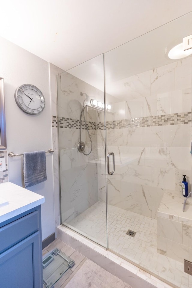 bathroom with a shower with door, vanity, and tile patterned floors