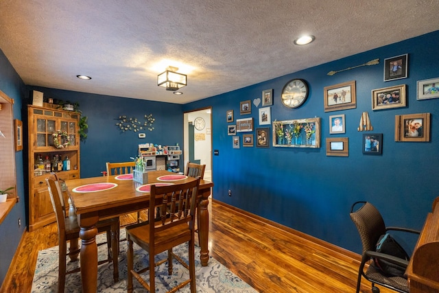 dining room featuring a textured ceiling and hardwood / wood-style floors