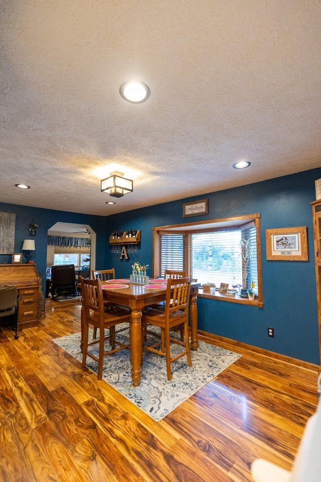 dining space with wood-type flooring and a textured ceiling