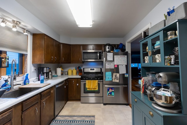 kitchen with stainless steel appliances, dark brown cabinetry, light tile patterned flooring, and sink