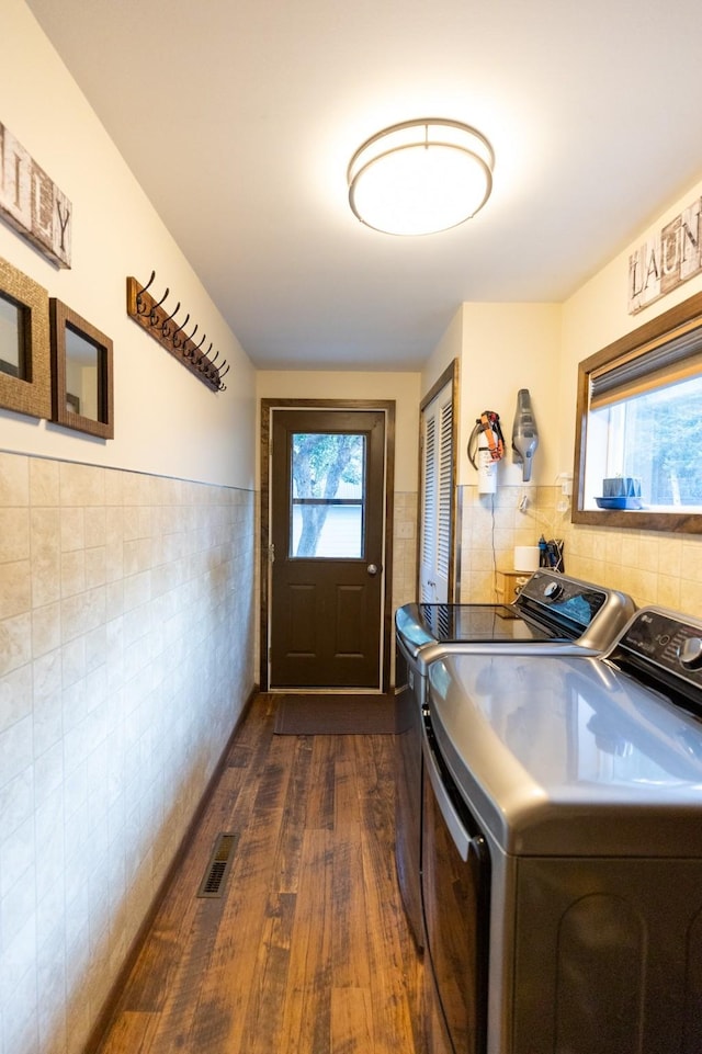 doorway to outside featuring separate washer and dryer, dark hardwood / wood-style flooring, and tile walls