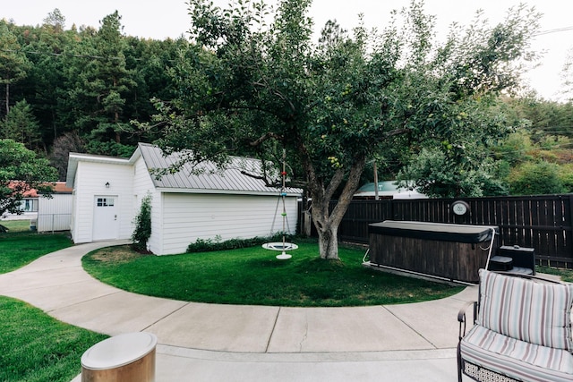 exterior space featuring a jacuzzi, an outbuilding, and a lawn