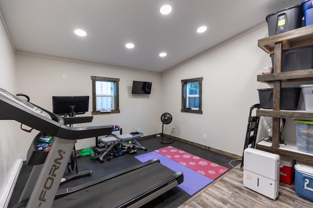 exercise area with wood-type flooring, a baseboard heating unit, ornamental molding, and vaulted ceiling