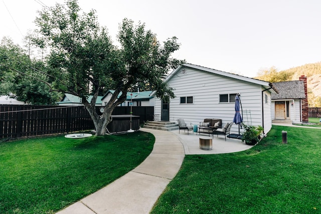 back of house with a lawn, a hot tub, and a patio