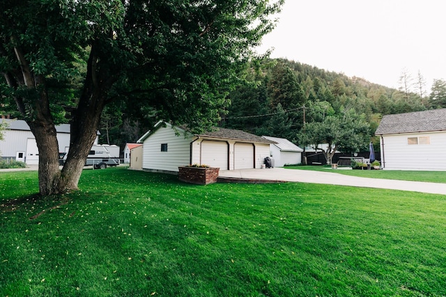 view of yard with a garage, an outbuilding, and a mountain view