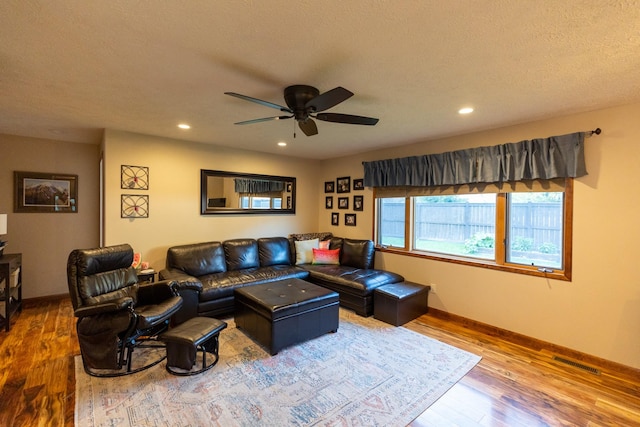 living room with wood-type flooring, a textured ceiling, and ceiling fan