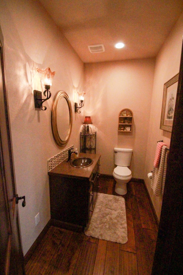 bathroom featuring toilet, vanity, and hardwood / wood-style floors