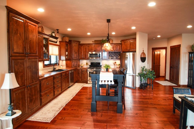 kitchen featuring stainless steel appliances, sink, decorative backsplash, a kitchen island, and dark hardwood / wood-style flooring