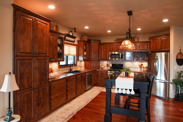 kitchen featuring appliances with stainless steel finishes, dark hardwood / wood-style floors, sink, decorative light fixtures, and backsplash