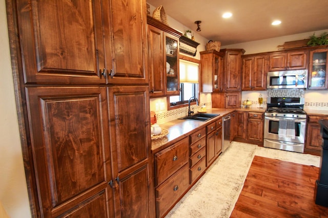 kitchen featuring sink, decorative backsplash, light hardwood / wood-style floors, and appliances with stainless steel finishes