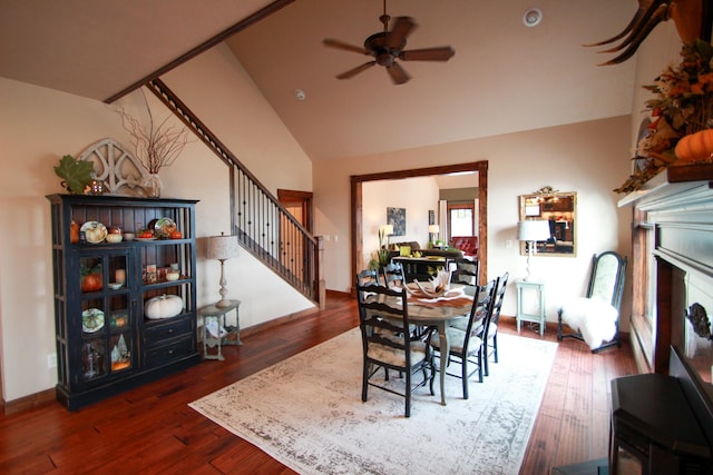 dining room featuring ceiling fan, dark wood-type flooring, vaulted ceiling, and a fireplace