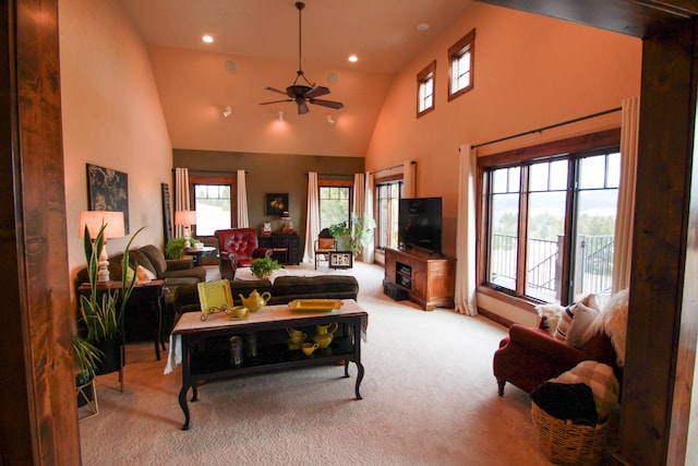 living room with a towering ceiling, ceiling fan, and light carpet